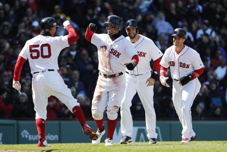 Xander Bogaerts, second from left, smiles as he is congratulated by Mookie Betts, left, after hitting a grand slam that scored Betts, Andrew Benintendi, right, and J.D. Martinez, second from right, in the second inning Saturday against the Tampa Bay Rays at Fenway Park in Boston.
