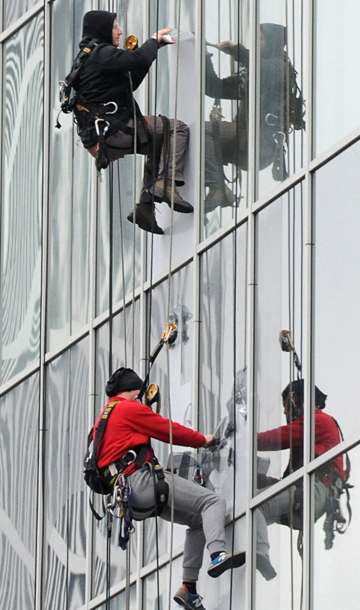Workers remove an advertisement from a glass facade of a building  in Warsaw, Poland. A tight labor market is jeopardizing the European Union's largest eastern economy.