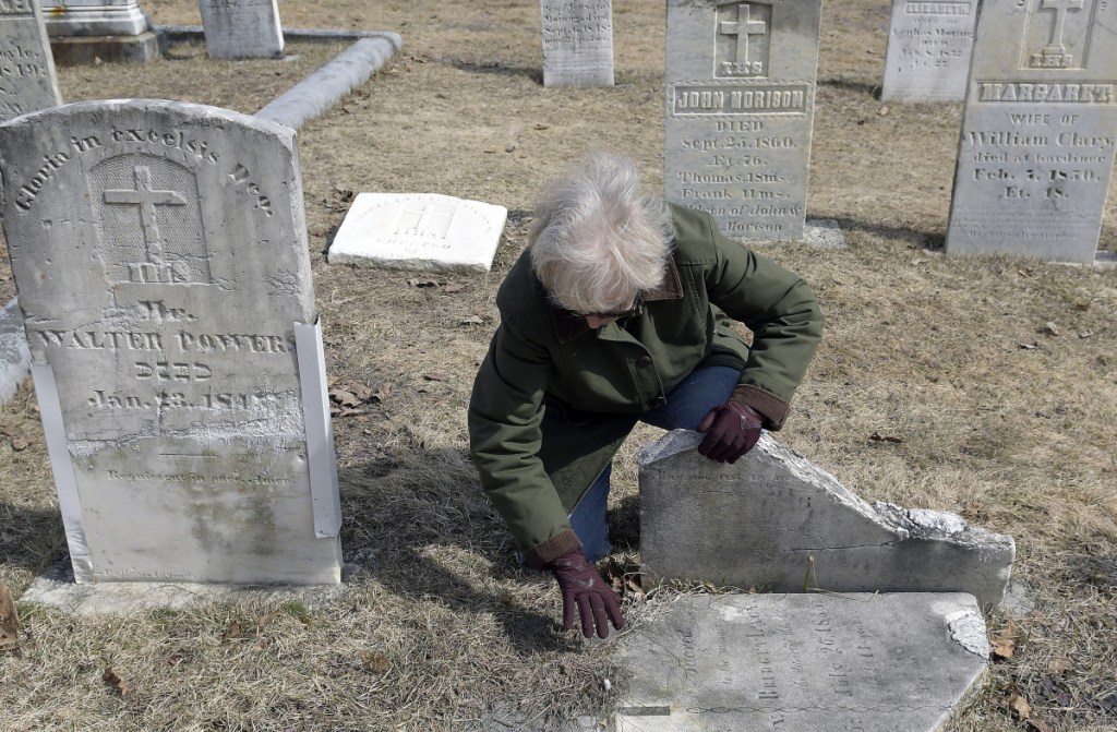 Whitefield archivist Libby Harmon uncovers the headstone of an Irish immigrant at St. Denis Cemetery in Whitefield.
