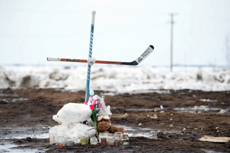 A memorial, including a cross made out of hockey sticks, sits near the intersection of a fatal bus crash near Tisdale, Saskatchewan, Canada, on Monday. A bus carrying the Humboldt Broncos junior hockey team collided with a truck Friday night, killing 15 and sending over a dozen more to the hospital.