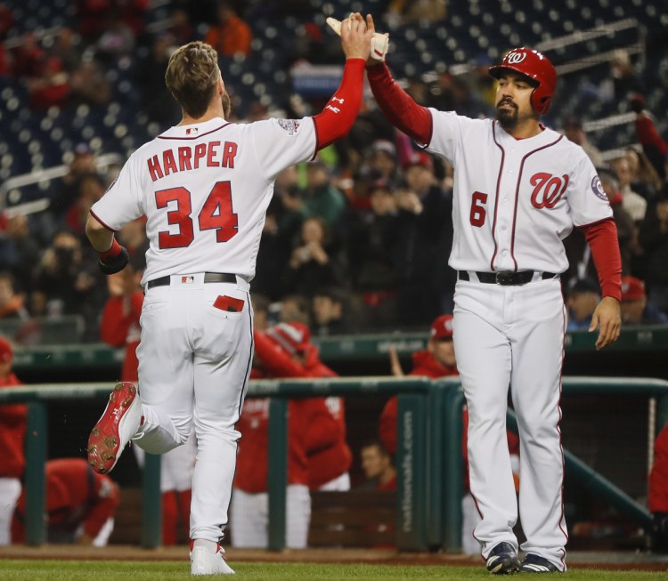 Bryce Harper of the Washington Nationals is greeted by teammate Anthony Rendon after they scored Monday night on a double by Howie Kendrick during the first inning of a 2-0 victory against the visiting Atlanta Braves.