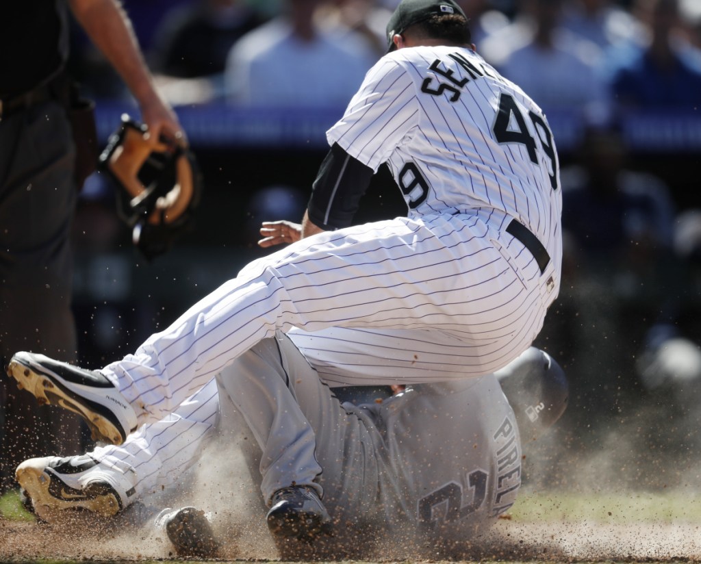Rockies relief pitcher Antonio Senzatela lands on the Padres' Jose Pirela, who scored on a passed ball in the sixth Wednesday in Denver. The Rockies won the brawl-marred game 6-4.