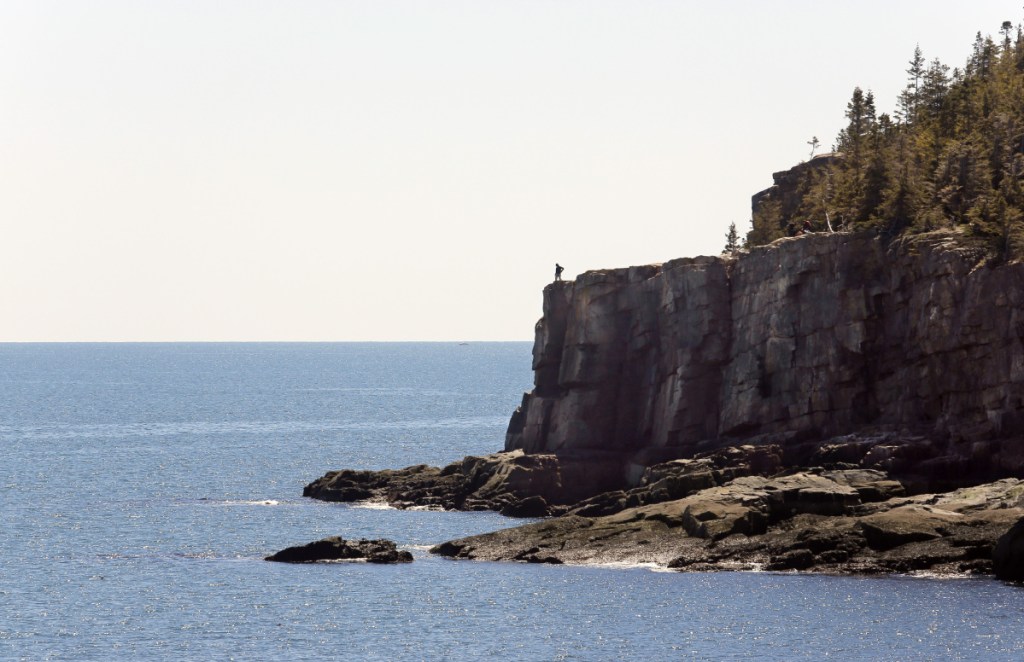A lone visitor looks out over the ocean from Otter Cliffs in Acadia National Park in 2016. Starting June 1, park entrance fees are going up by $5.