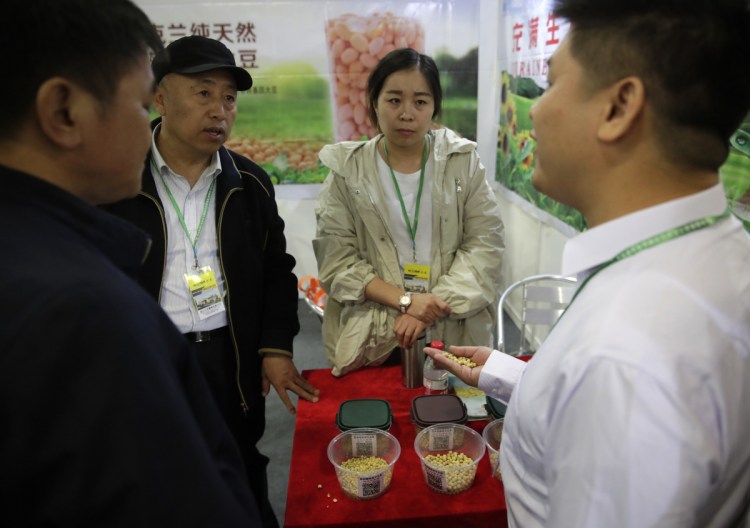 A Chinese exhibitor explains to visitors about his company's raw soybeans at an international trade exhibition Thursday in Shanghai. China's global trade balance swung to a rare deficit in March as exports contracted 2.7% from a year earlier.