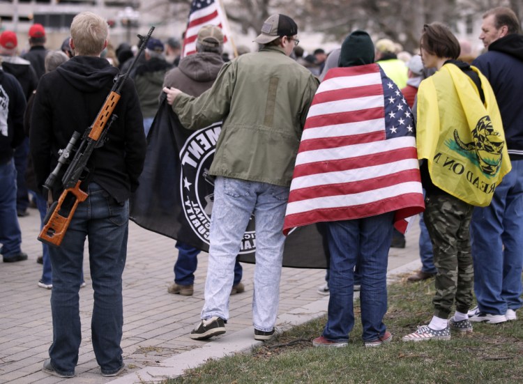 Pro-gun supporters wrapped in flags and carrying guns rally at the Kansas Statehouse in Topeka on Saturday. The rallies come less than three weeks after hundreds of thousands marched in Washington, New York and elsewhere to demand tougher gun laws after the February school shooting in Parkland, Fla.