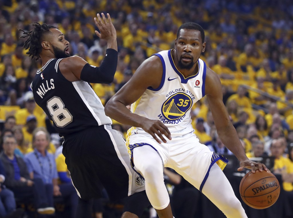 Golden State's Kevin Durant, right, drives the ball around San Antonio's Patty Mills during the first half in Game 1 of a first-round NBA basketball playoff series on Saturday.
