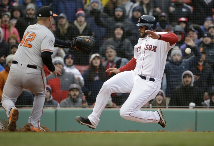 Boston's J.D. Martinez, right, scores on a wild pitch by Baltimore's Dylan Bundy, left, in the sixth inning Sunday in Boston.