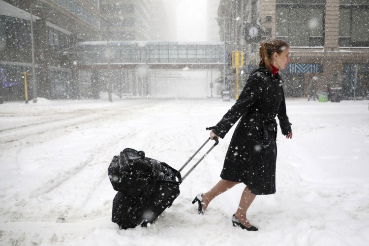 Delta Airlines flight attendant Victoria Flees trudges through the snow with her bags in downtown Minneapolis after her flight to Paris was grounded because of weather.
