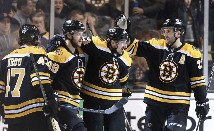 David Pastrnak, second from left, is congratulated by Torey Krug, left, Brad Marchand, center, and Patrice Bergeron after he scored his third goal of the game Saturday in Boston's 7-3 win over the Maple Leafs.