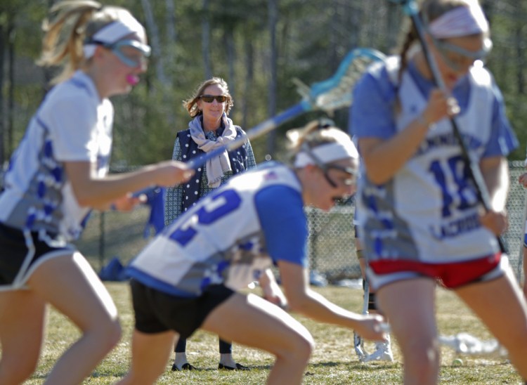 Kennebunk girls' lacrosse coach Annie Barker watches her players run through a drill. Kennebunk, winners of the past two Class B championships, moves up to Class A this season as the sport adds a third enrollment class. (Staff photo by Gregory Rec/Staff Photographer)