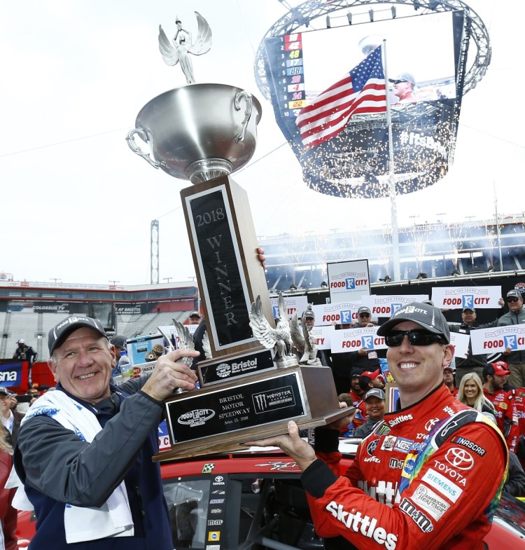 Food City President and CEO Steve Smith, left, holds the trophy with race winner Kyle Busch after the NASCAR Cup Series race on Monday in Bristol, Tenn.