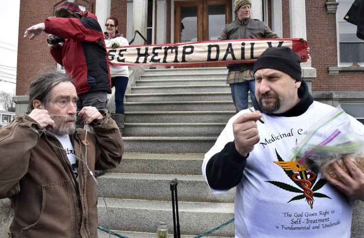 Marijuana advocate Donny Christen, left, who suffers chronic obstructive pulmonary disease, inserts oxygen tubes to help him breathe, as medicinal caregiver Dennis Hammac smokes a joint and distributes edible pot products at the annual Patriot's Day smoke-in at the Somerset County Courthouse.