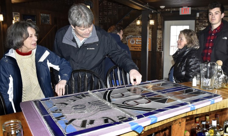 McCarthy family members, from left, Judie, Rick, Julie and Kael, look over the stained glass window that greeted customers inside the Old Mill Pub in Skowhegan that the family once owned after it was removed on Monday. Current owner Greg Dore gave the family the original window and replaced it with a new one.