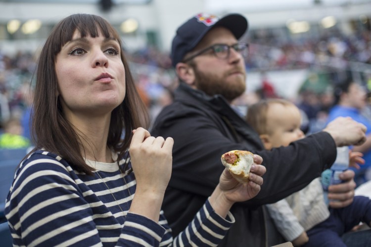 Portland restaurateurs Briana and Andrew Volk, with their 11-month-old son, Rockwell, watch the Sea Dogs' home opener at Hadlock Field on Friday. Their sandwich pick? Ballpark franks.