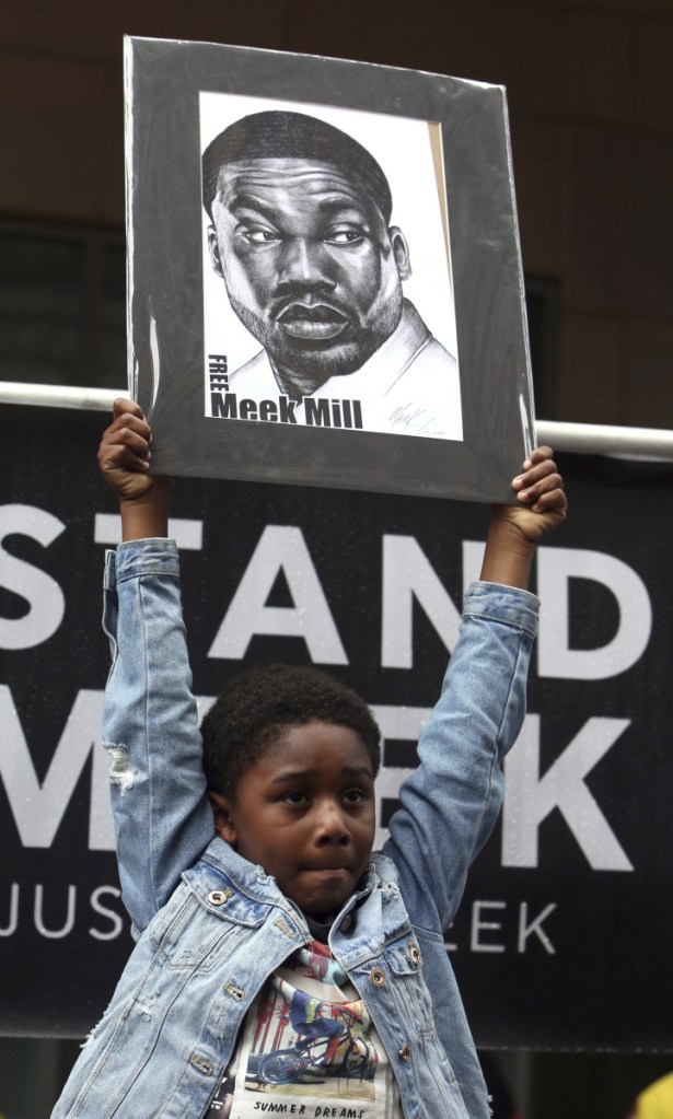Rapper Meek Mill's son Papi holds a sign as protesters demonstrate in front of a courthouse during a hearing for the rapper in Philadelphia.