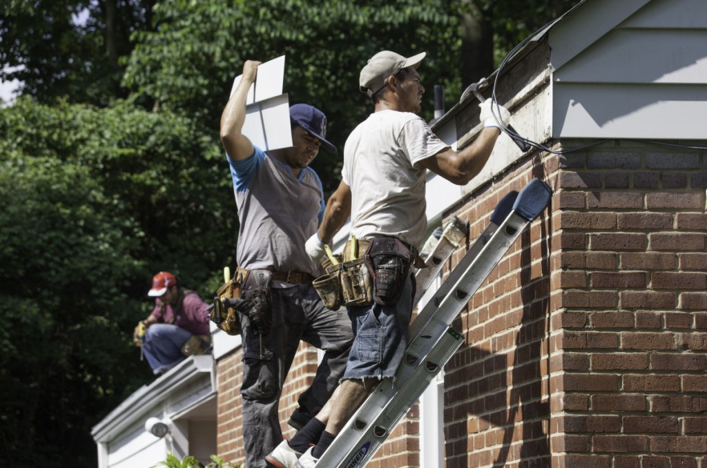 A work crew installs gutters and patches up a roof at a house in Fairfax County, Va. With an acute shortage of carpenters, electricians, plumbers and many other trade workers across the United States, many home owners are finding it difficult to maintain their properties.