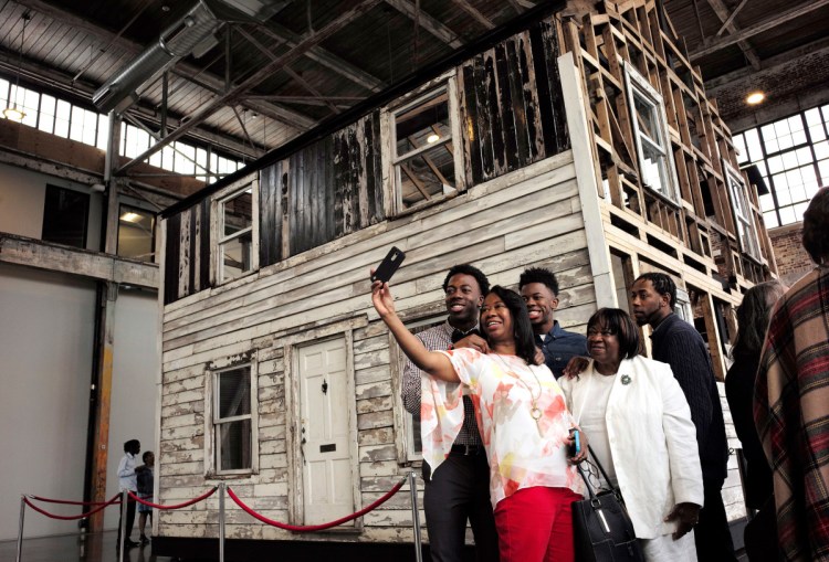 Cheryl Galloway of Providence, R.I., front, uses a mobile phone to take a photo with family members in front of the rebuilt house of Rosa Parks in Providence earlier this month.