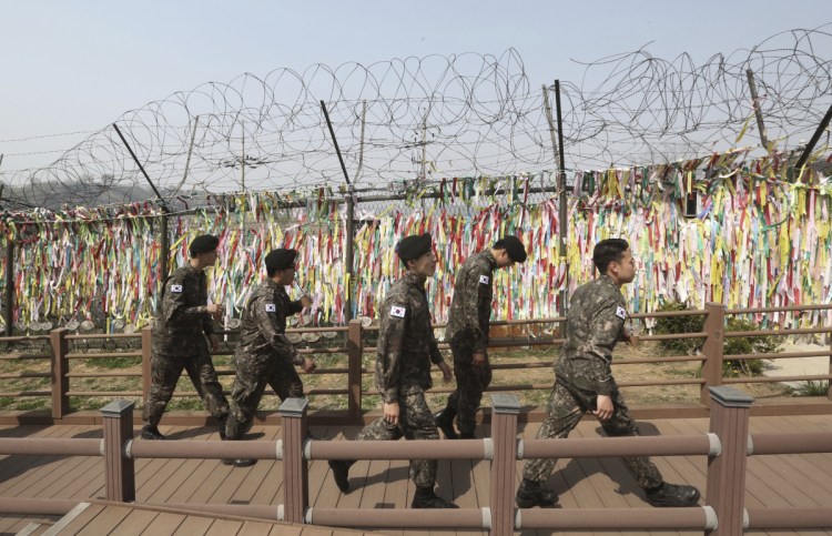 South Korean soldiers pass by a wire fence decorated with ribbons written with messages wishing for the reunification of the two Koreas at the Imjingak Pavilion in Paju, South Korea, near the border with North Korea, on Friday. North and South Korea installed the first-ever telephone hotline between their leaders Friday as they prepare for a rare summit next week aimed at resolving the nuclear standoff with Pyongyang.