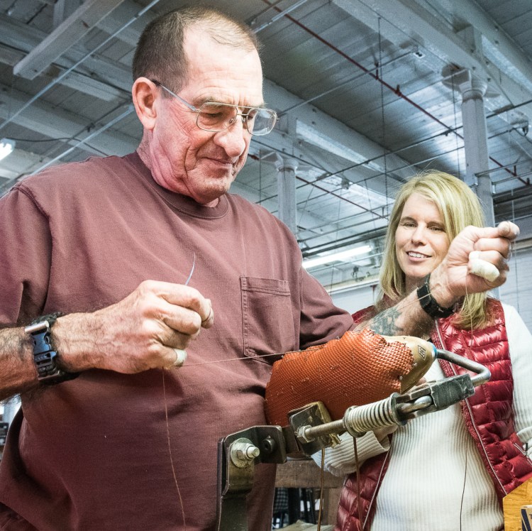 Mary Mayhew, right, watches Quoddy hand sewer Paul Leathers make a pair of boat shoes at the Lewiston shoe shop Friday morning. Leathers has been sewing for a number of companies since 1963.