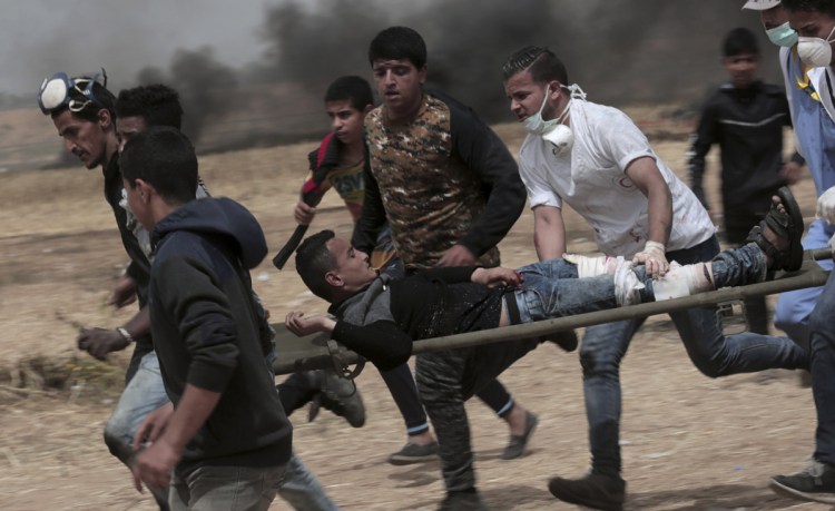 Palestinian protesters evacuate a wounded youth during clashes with Israeli troops along Gaza's border with Israel, east of Khan Younis in the Gaza Strip on Friday.