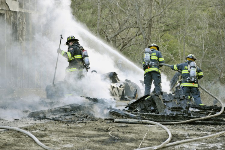 Firefighters extinguish hot spots Saturday after battling a fatal blaze in West Falmouth.