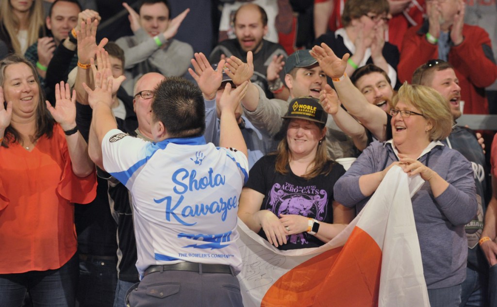 Shota Kawazoe of Japan high-fives fans after rolling a strike during the Elias Cup professional bowling event Saturday at Bayside Bowl in Portland. There were plenty of strikes and spares, but the packed crowd came for the fun, and found plenty of it.