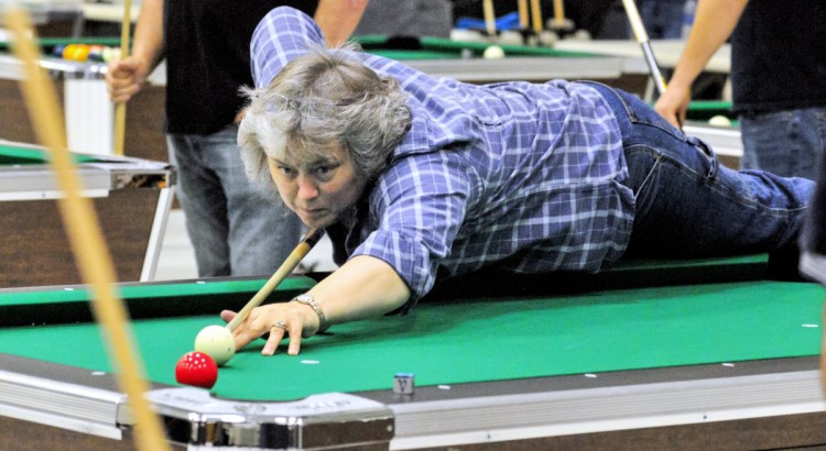 Manchester resident Chrystal Violette, a member of the Need a New Rack women's team, leans onto the table to make a shot during Sunday's event at the Augusta Armory.