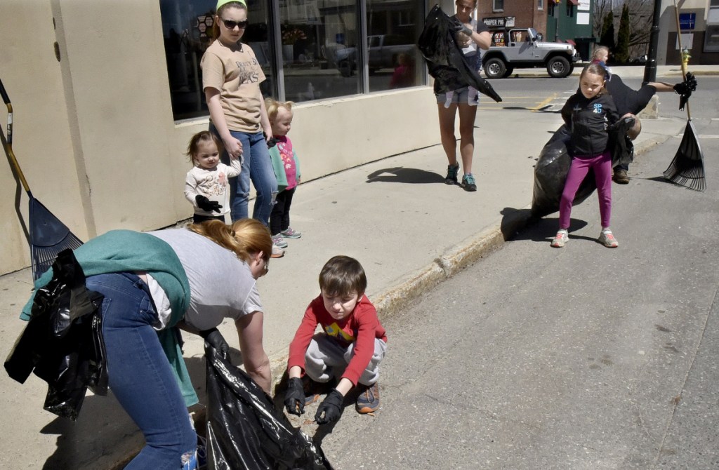 Molly Re holds a bag open for her son William to throw trash into as they and other family and friends helped pick up litter near the Concourse in Waterville as part of the Earth Day celebration on Sunday.