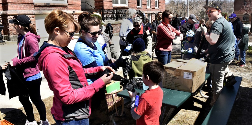 Todd Martin, right, hands out trash bags and gloves to volunteers who helped pick up litter near the Concourse in Waterville as part of the Earth Day celebration on Sunday.
