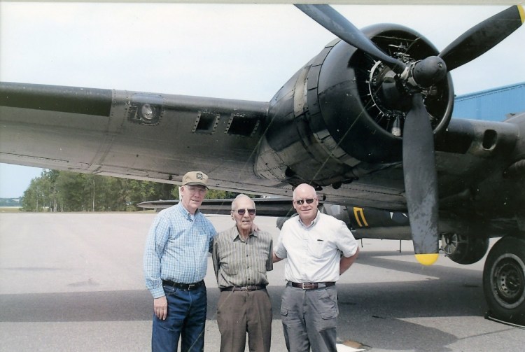 Al Kramer, center, with his neighbors from China village, Don Pauley, left, and Craig Poulin beneath the wing of a B-17 World War II bomber in New Hampshire in 2013. Kramer was shot down over France during WWII while piloting a B-17.