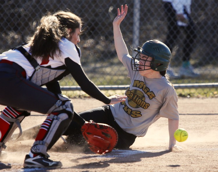 Holly Akey of Maine Girls' Academy slides into the plate, beating a throw to South Portland catcher Ashley Aceto in the first inning of South Portland's 16-10 victory Monday.