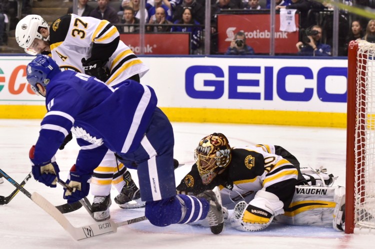 Boston Bruins goaltender Tuukka Rask gets low to watch for the puck as teammate Patrice Bergeron  battles Toronto Maple Leafs center Zach Hyman during the third period of Game 6 of their first round playoff series on Monday in Toronto. The Maple Leafs won 3-1 to force Game 7.