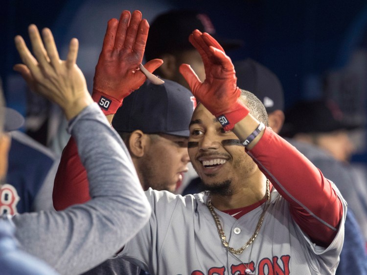 Mookie Betts celebrates with Red Sox teammates in the dugout after hitting the first of his two home runs Wednesday night in a 4-3 victory over the Toronto Blue Jays.