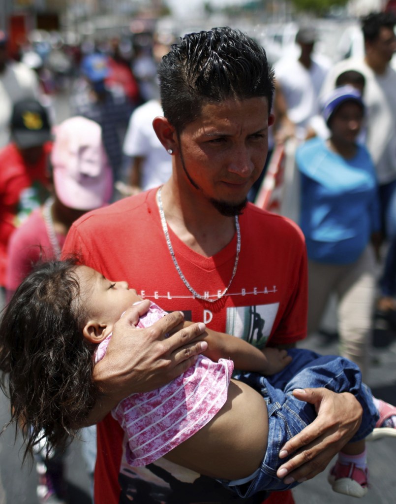 A migrant traveling with the annual Stations of the Cross caravan carries a little girl during a march for migrants' rights in Hermosillo, Mexico.