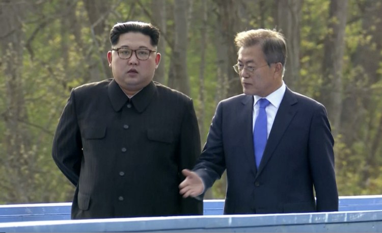 North Korean leader Kim Jong Un, left, and South Korean President Moon Jae-in, right, talk as they walk on blue bridge in the border village of Panmunjom in the Demilitarized Zone on Friday.
