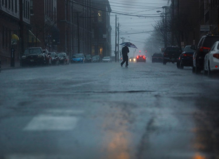  A man crosses Pearl Street, Portland, in the rain on April 16. 