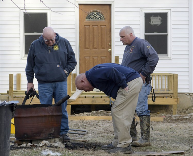 Office of State Fire Marshal investigator Ken MacMaster, left, Winthrop Fire Chief Dan Brooks and Winthrop firefighter Mark Arsenault inspect a burn barrel Tuesday outside a residence in Winthrop. The resident of the Old Lewiston Road residence suffered serious burns to his lower extremities when the boots he was wearing caught fire, according to Winthrop Deputy Fire Chief David Currie. 