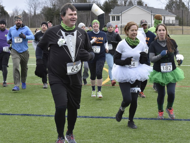Bill Jackson and Jennifer Denis, both of Randolph, wore wedding outfits as they take off running in the Thomas College Dirty Dog Mud Run.