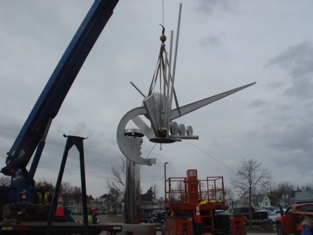 Ben Lavigne, left, of The Cote Corp. operates the crane that lifts the crown of "The Ticonic" sculpture from its pedestal Wednesday morning.
