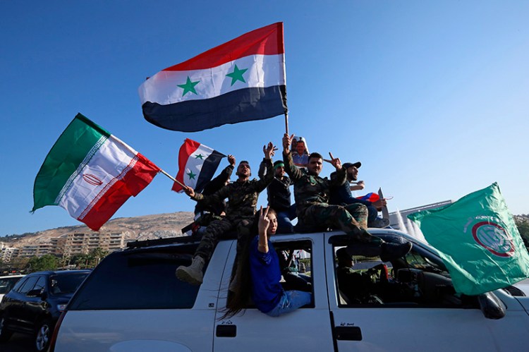 Syrian government supporters wave Syrian, Iranian and Russian flags as they chant slogans against U.S. President Trump during demonstrations following a wave of U.S., British and French military strikes .