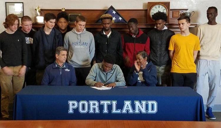Portland senior standout Terion Moss, joined by his mother, Valerie, Bulldogs coach Joe Russo and several teammates, signs his National Letter of Intent Wednesday morning.