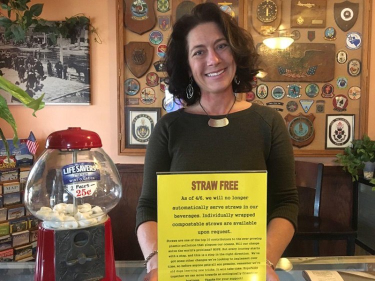 Cheri Siatras, who co-owns Joshua's Restaurant & Tavern in Brunswick, holds a sign announcing the decision to go plastic straw-free. 