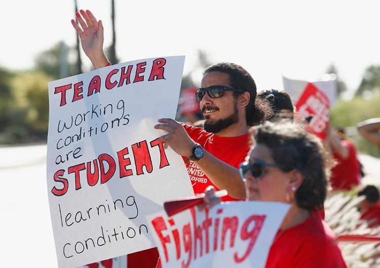 Teachers, parents and students line up along a street in Phoenix, waving to passing vehicles for the latest teacher protest for higher teacher pay and school funding on Wednesday.