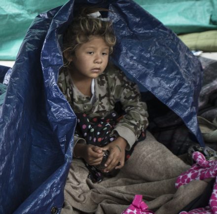 A girl who traveled with the caravan of Central American migrants awakens where the group set up camp to wait for access to request asylum in the U.S., outside the El Chaparral port of entry building at the US-Mexico border in Tijuana, Mexico, on Tuesday.