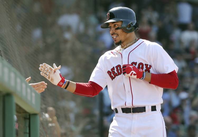 Mookie Betts celebrates at the dugout after hitting his third home run of the game in the seventh inning on Wednesday afternoon against the Kansas City Royals at Fenway Park in Boston.