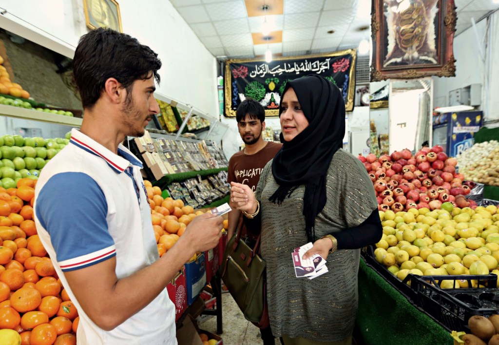 Sahira Falih, a candidate for parliamentary elections, speaks with a vegetable seller as she campaigns in April at a market in Baghdad, Iraq.  Women candidates face many challenges.