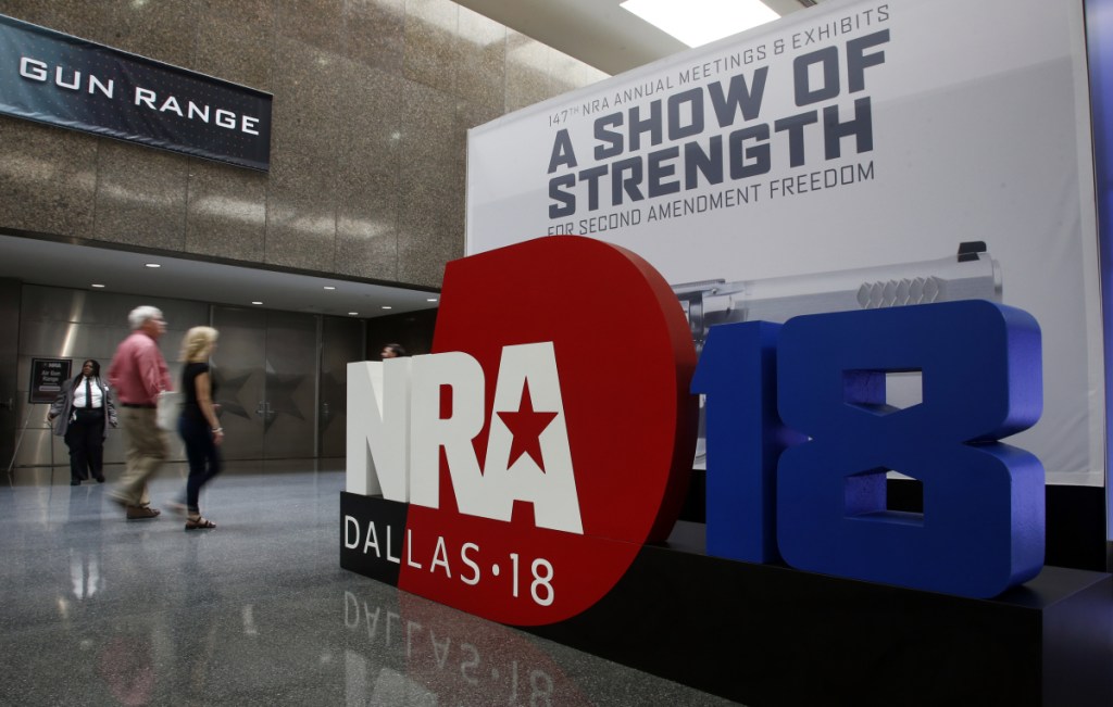 People walk past NRA convention signage at the Kay Bailey Hutchison Convention Center in Dallas. Several groups plan to protest outside the event, which runs through Sunday.