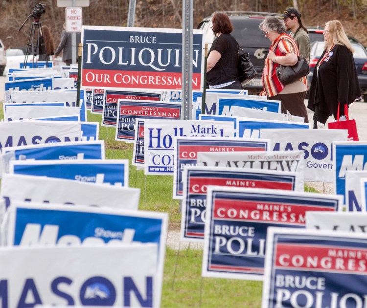 During lunch break Friday, people walk past signs outside the Augusta Civic Center during the Maine Republican Party convention. (Staff photo by Joe Phelan/Staff Photographer)
