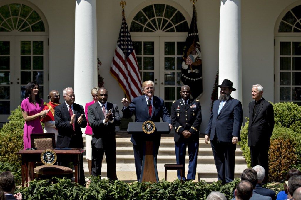 President Trump, center, speaks next to guests from faith-based communities during a National Day of Prayer ceremony in the Rose Garden of the White House on Thursday. MUST CREDIT: Bloomberg photo by Andrew Harrer
