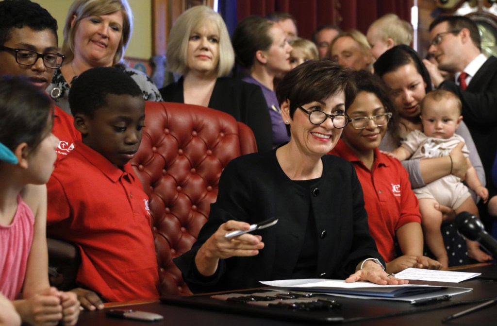 Iowa Gov. Kim Reynolds signs a six-week abortion ban bill into law during a ceremony Friday in Des Moines. The law gives Iowa the strictest abortion restrictions in the nation.